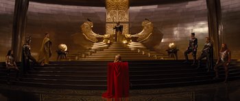 Movie still from “Thor” (2011), directed by Kenneth Branagh – A woman in a red cloak standing in front of a golden throne; Extreme Wide shot, High angle