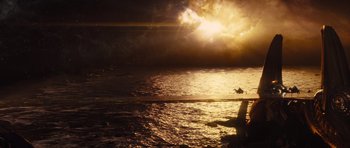 Movie still from “Thor” (2011), directed by Kenneth Branagh – An airplane flying over a body of water at sunset; Extreme Wide shot, Over the shoulder angle