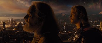 Movie still from “Thor” (2011), directed by Kenneth Branagh – A man and a woman standing next to each other in front of a city skyline; Close Up shot, Low angle