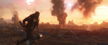 Movie still from “Thor: Love and Thunder” (2022), directed by Taika Waititi – A man is running through a field with smoke coming out of the sky; Wide shot, Low angle