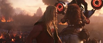 Movie still from “Thor: Love and Thunder” (2022), directed by Taika Waititi – A man with long blonde hair standing in front of a robot; Medium shot, Low angle