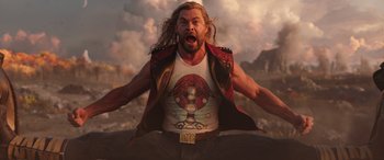 Movie still from “Thor: Love and Thunder” (2022), directed by Taika Waititi – A man with long hair and a shirt with a design on it; Medium shot, Low angle