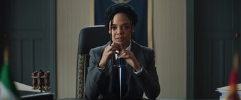 Movie still from “Thor: Love and Thunder” (2022), directed by Taika Waititi – A woman sitting at a desk in front of a microphone; Medium shot, Low angle