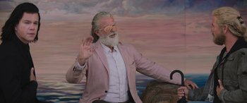 Movie still from “Thor: Love and Thunder” (2022), directed by Taika Waititi – An old man with a long white beard waves; Medium shot, Over the shoulder angle