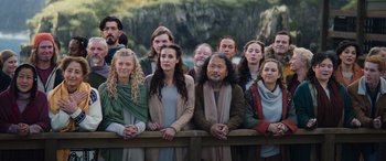 Movie still from “Thor: Love and Thunder” (2022), directed by Taika Waititi – A group of people standing next to each other on top of a wooden fence; Wide shot, High angle
