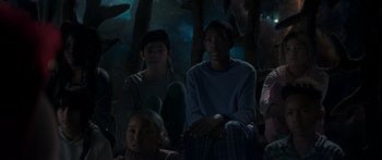 Movie still from “Thor: Love and Thunder” (2022), directed by Taika Waititi – A group of people sitting in the woods at night; Medium shot, Low angle