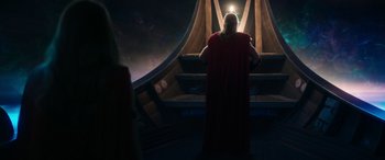 Movie still from “Thor: Love and Thunder” (2022), directed by Taika Waititi – A man in a red robe standing in front of a light; Medium shot, Low angle