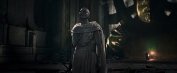 Movie still from “Thor: Love and Thunder” (2022), directed by Taika Waititi – An old man in a roman outfit standing next to a statue; Medium shot, Low angle