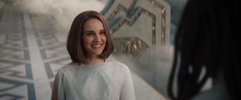 Movie still from “Thor: Love and Thunder” (2022), directed by Taika Waititi – A woman in a white shirt smiling for the camera; Close Up shot, Over the shoulder angle