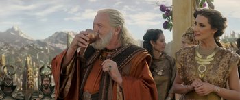 Movie still from “Thor: Ragnarok” (2017), directed by Taika Waititi – An older man with long white hair and a long white beard drinking from a cup; Medium shot, Over the shoulder angle