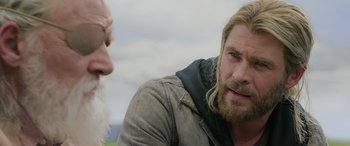Movie still from “Thor: Ragnarok” (2017), directed by Taika Waititi – A man with long blond hair and a white beard is talking to another man with long blond hair; Close Up shot, Over the shoulder angle