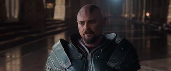 Movie still from “Thor: Ragnarok” (2017), directed by Taika Waititi – A man with a bald head wearing armor; Close Up shot, Over the shoulder angle