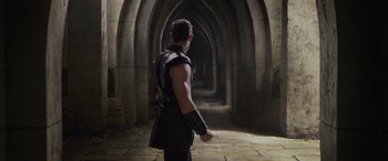 Movie still from “Thor: Ragnarok” (2017), directed by Taika Waititi – A man in a black leather outfit stands in an archway; Medium shot, Over the shoulder angle