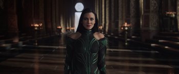 Movie still from “Thor: Ragnarok” (2017), directed by Taika Waititi – A woman in a green and black costume stands in front of a window; Medium shot, Over the shoulder angle
