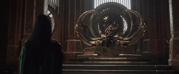 Movie still from “Thor: Ragnarok” (2017), directed by Taika Waititi – A man sitting on a throne in a room; Wide shot, Over the shoulder angle