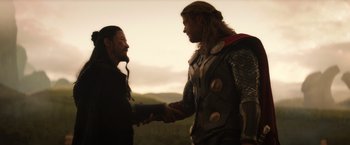Movie still from “Thor: The Dark World” (2013), directed by Alan Taylor – Two men are shaking hands while standing in the grass; Medium shot, Over the shoulder angle