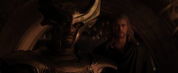 Movie still from “Thor: The Dark World” (2013), directed by Alan Taylor – A man with a helmet on and a man with blond hair in the background; Close Up shot, Over the shoulder angle