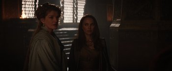 Movie still from “Thor: The Dark World” (2013), directed by Alan Taylor – Two women standing next to each other in a dark room; Medium shot, Over the shoulder angle