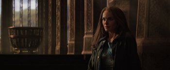 Movie still from “Thor: The Dark World” (2013), directed by Alan Taylor – A woman standing in front of stained glass windows; Medium shot, Over the shoulder angle
