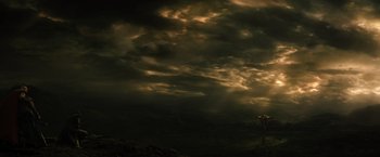 Movie still from “Thor: The Dark World” (2013), directed by Alan Taylor – A person standing on top of a hill under a cloudy sky; Extreme Wide shot, Low angle