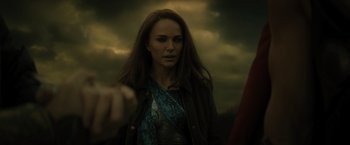 Movie still from “Thor: The Dark World” (2013), directed by Alan Taylor – A woman with long red hair standing in front of a cloudy sky; Close Up shot, Over the shoulder angle