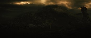 Movie still from “Thor: The Dark World” (2013), directed by Alan Taylor – A person standing in a field near a mountain under a cloudy sky; Extreme Wide shot, Low angle
