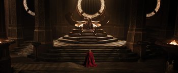 Movie still from “Thor: The Dark World” (2013), directed by Alan Taylor – A woman in a red dress sitting on a staircase; Extreme Wide shot, High angle