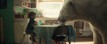 Movie still from “Timmy Failure: Mistakes Were Made” (2020), directed by Tom McCarthy – A white polar bear eating food from a table; Medium shot, Low angle