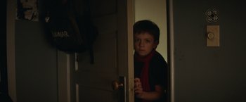 Movie still from “Timmy Failure: Mistakes Were Made” (2020), directed by Tom McCarthy – A young boy wearing a red scarf standing in a doorway; Close Up shot, High angle