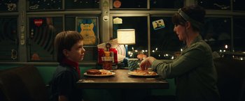 Movie still from “Timmy Failure: Mistakes Were Made” (2020), directed by Tom McCarthy – Two people sitting at a table eating pizza; Medium shot, Over the shoulder angle