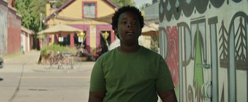 Movie still from “Timmy Failure: Mistakes Were Made” (2020), directed by Tom McCarthy – A young man standing in front of a colorful building; Medium shot, Low angle