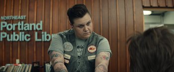 Movie still from “Timmy Failure: Mistakes Were Made” (2020), directed by Tom McCarthy – A person with tattoos sitting in a room; Medium shot, Over the shoulder angle