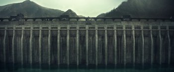 Movie still from “Timmy Failure: Mistakes Were Made” (2020), directed by Tom McCarthy – A large concrete wall with a train on top of it near a body of water; Extreme Wide shot, Low angle