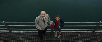 Movie still from “Timmy Failure: Mistakes Were Made” (2020), directed by Tom McCarthy – A man standing next to a boy on a metal railing; Medium shot, Overhead angle