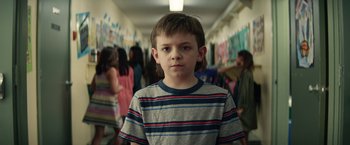 Movie still from “Timmy Failure: Mistakes Were Made” (2020), directed by Tom McCarthy – A young boy standing in a school hallway; Close Up shot, Over the shoulder angle