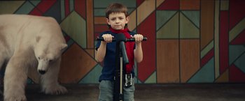 Movie still from “Timmy Failure: Mistakes Were Made” (2020), directed by Tom McCarthy – A young boy is standing on a scooter; Medium shot, Over the shoulder angle