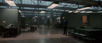 Movie still from “Tinker Tailor Soldier Spy” (2011), directed by Tomas Alfredson – A man standing in an empty room next to a table; Wide shot, High angle