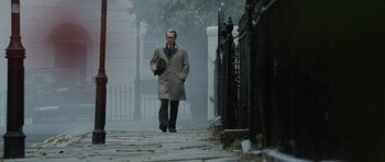 Movie still from “Tinker Tailor Soldier Spy” (2011), directed by Tomas Alfredson – A man walking down the street in a trench coat; Wide shot, Low angle