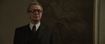Movie still from “Tinker Tailor Soldier Spy” (2011), directed by Tomas Alfredson – A man in a suit and tie standing in front of a wall; Medium shot, Low angle