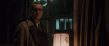 Movie still from “Tinker Tailor Soldier Spy” (2011), directed by Tomas Alfredson – A man standing in front of a lamp in front of a window; Medium shot, Low angle