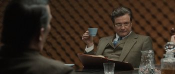 Movie still from “Tinker Tailor Soldier Spy” (2011), directed by Tomas Alfredson – A man sitting at a table holding a coffee cup; Medium shot, Over the shoulder angle