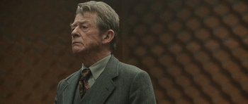Movie still from “Tinker Tailor Soldier Spy” (2011), directed by Tomas Alfredson – An older man wearing a suit and tie; Close Up shot, Over the shoulder angle