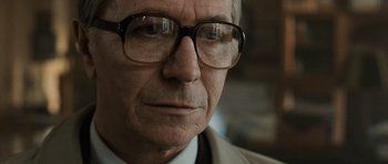 Movie still from “Tinker Tailor Soldier Spy” (2011), directed by Tomas Alfredson – An older man wearing glasses looking at the camera; Close Up shot, Over the shoulder angle