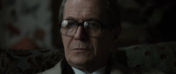 Movie still from “Tinker Tailor Soldier Spy” (2011), directed by Tomas Alfredson – An older man wearing glasses and a suit; Close Up shot, Over the shoulder angle