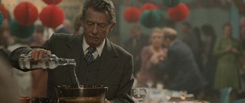 Movie still from “Tinker Tailor Soldier Spy” (2011), directed by Tomas Alfredson – An older man in a suit and tie sitting at a table; Close Up shot, Over the shoulder angle
