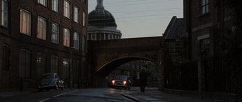 Movie still from “Tinker Tailor Soldier Spy” (2011), directed by Tomas Alfredson – A man walking across a street under a bridge; Extreme Wide shot, Low angle