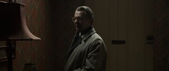 Movie still from “Tinker Tailor Soldier Spy” (2011), directed by Tomas Alfredson – A man in a trench coat standing in the dark; Medium shot, Over the shoulder angle