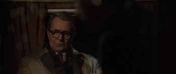 Movie still from “Tinker Tailor Soldier Spy” (2011), directed by Tomas Alfredson – An older man wearing glasses and a suit; Close Up shot, Over the shoulder angle