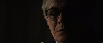 Movie still from “Tinker Tailor Soldier Spy” (2011), directed by Tomas Alfredson – An older man wearing glasses looking at the camera; Close Up shot, Low angle