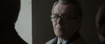 Movie still from “Tinker Tailor Soldier Spy” (2011), directed by Tomas Alfredson – An older man wearing glasses and a suit; Close Up shot, Over the shoulder angle